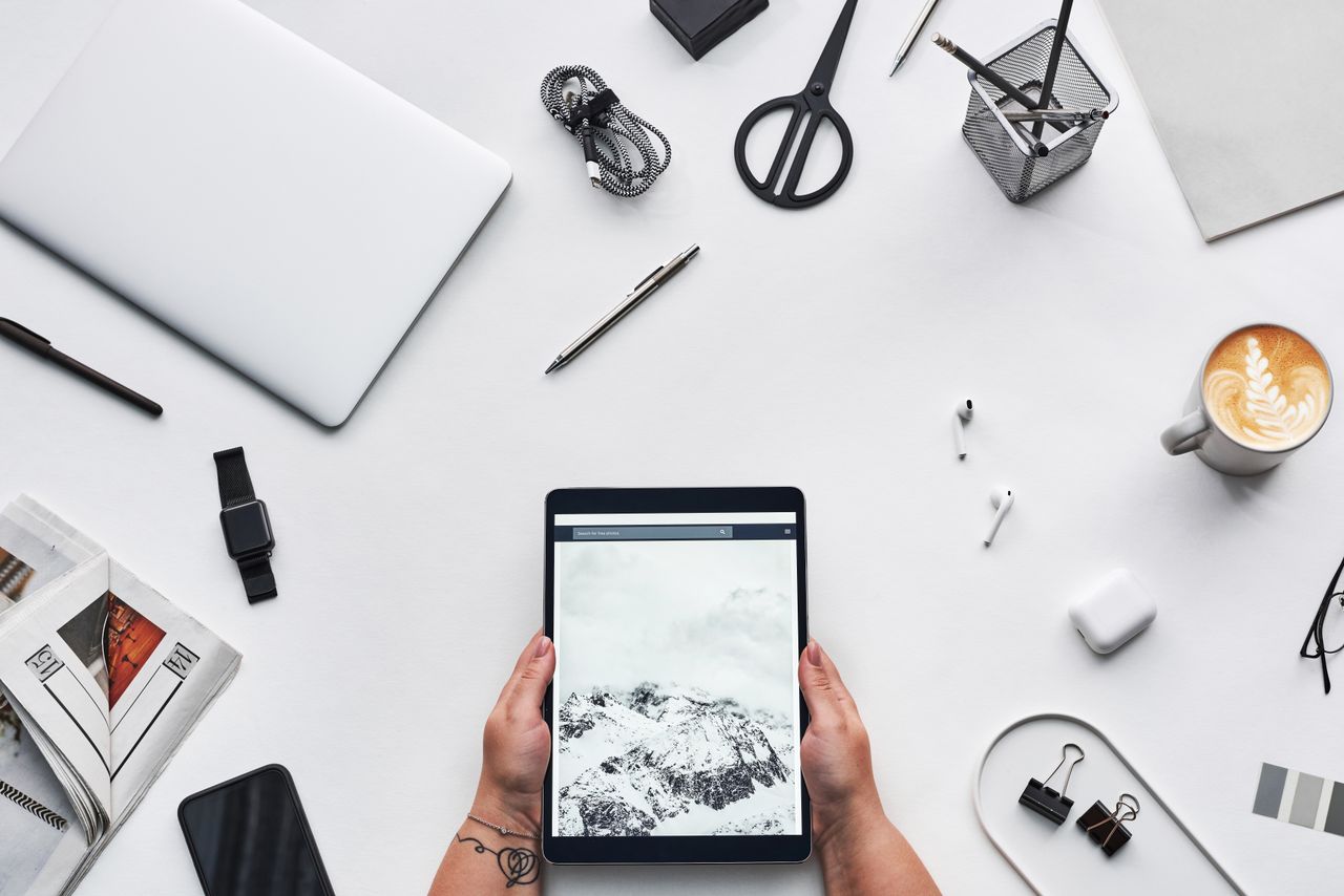 heros-img Flat lay of a modern workspace featuring a tablet, gadgets, and coffee for creative work.